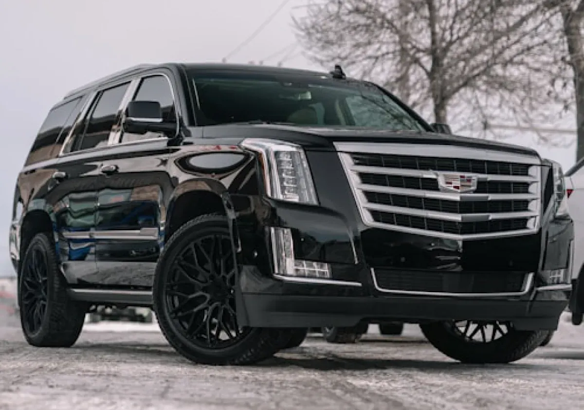 Чёрный Cadillac Escalade на зимней дороге, вид спереди три четверти