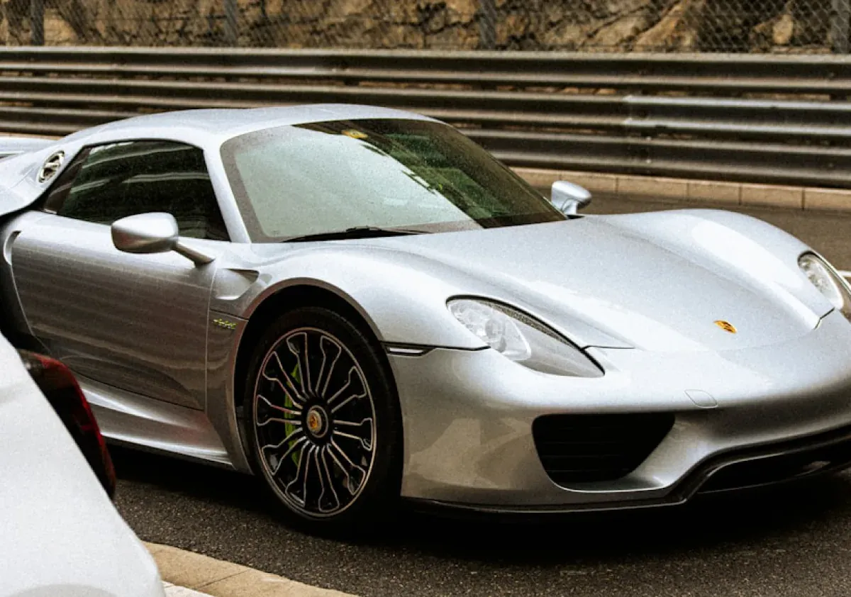 Серебристый Porsche 918 Spyder у ограждения гоночной трассы