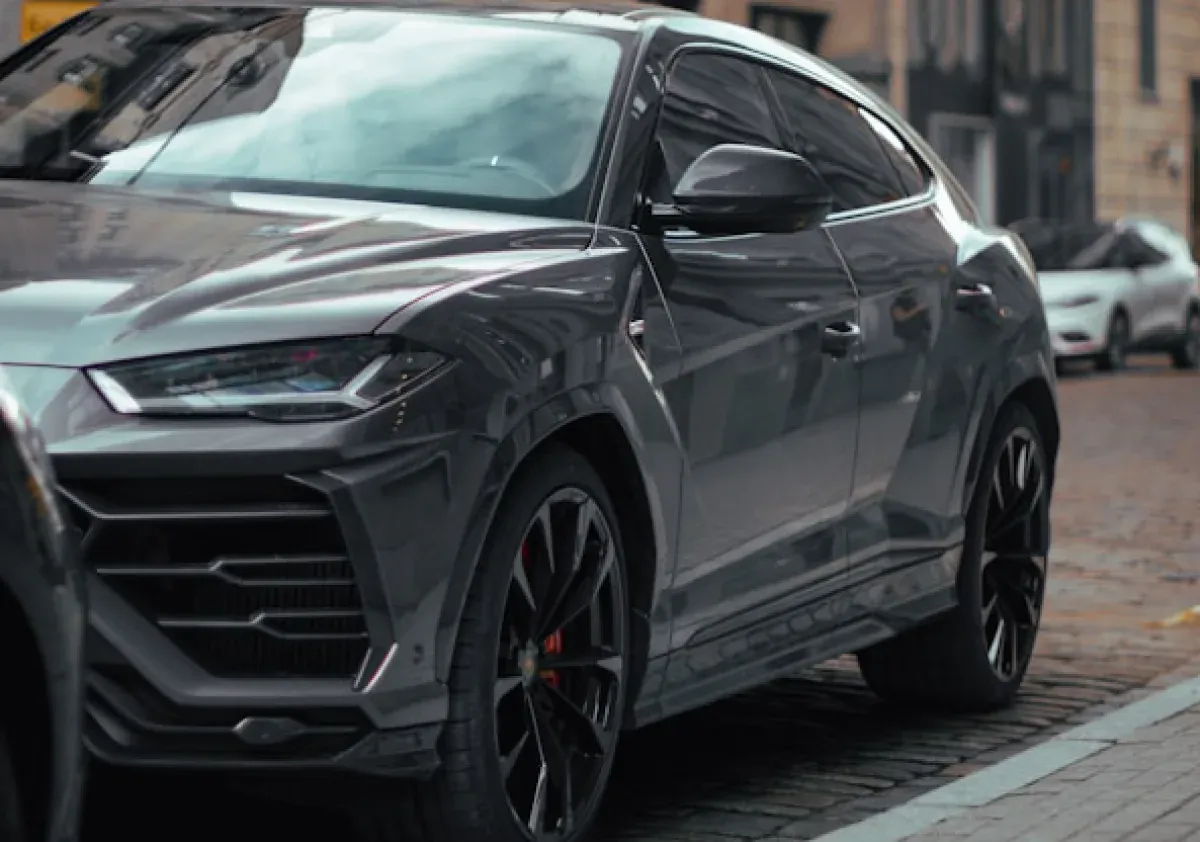 Тёмно-серый Lamborghini Urus у тротуара на городской улице